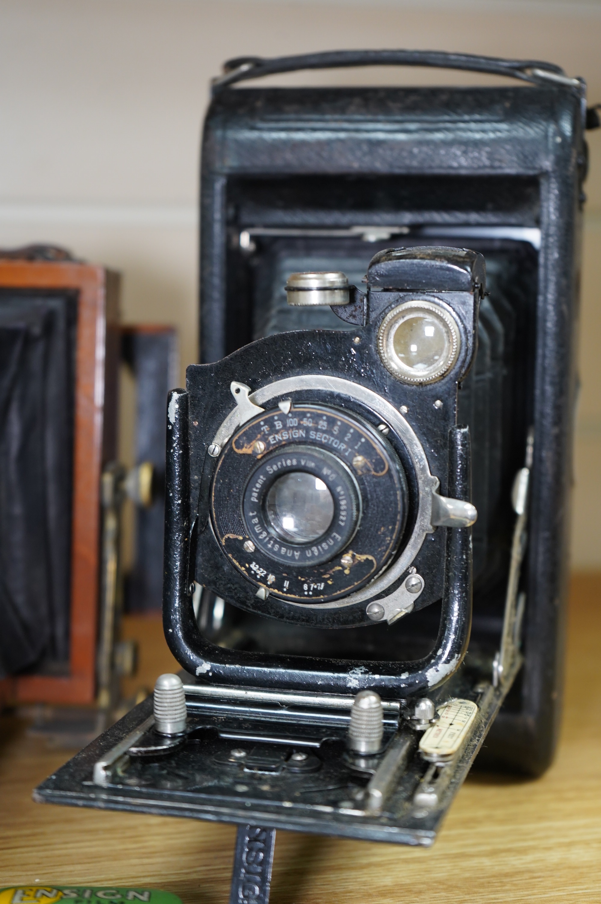 Two cameras; one late 19th century by Lancaster & Son, together with an Ensign bellows camera with two tins of spools of film. Condition - fair to good